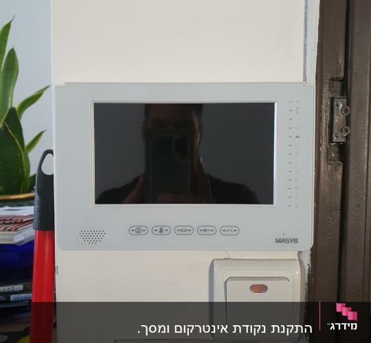 מסך אינטרקום עם כפתורים על קיר לבן